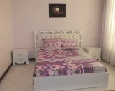 تخت خواب با روتختی رنگی و میز عسلی سفید اتاق خواب آپارتمان در کردکوی
