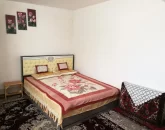 تخت خواب با روتختی رنگی و پشتی اتاق خواب خانه روستایی در گنبدکاووس