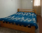 تخت خواب چوبی با روتختی آبی و کمددیواری سفید رنگ اتاق خواب ویلا در گرگان