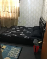 تخت خواب با روتختی مشکی و پرده کرمی رنگ اتاق خواب آپارتمان در رامیان