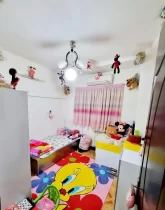 تخت خواب با روتختی عروسکی و کمد و عروسک در اتاق خواب آپارتمان در گنبدکاووس