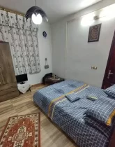 تخت خواب با روتختی آبی و پرده سفید و کمد در اتاق خواب خانه مسکونی در گالیکش